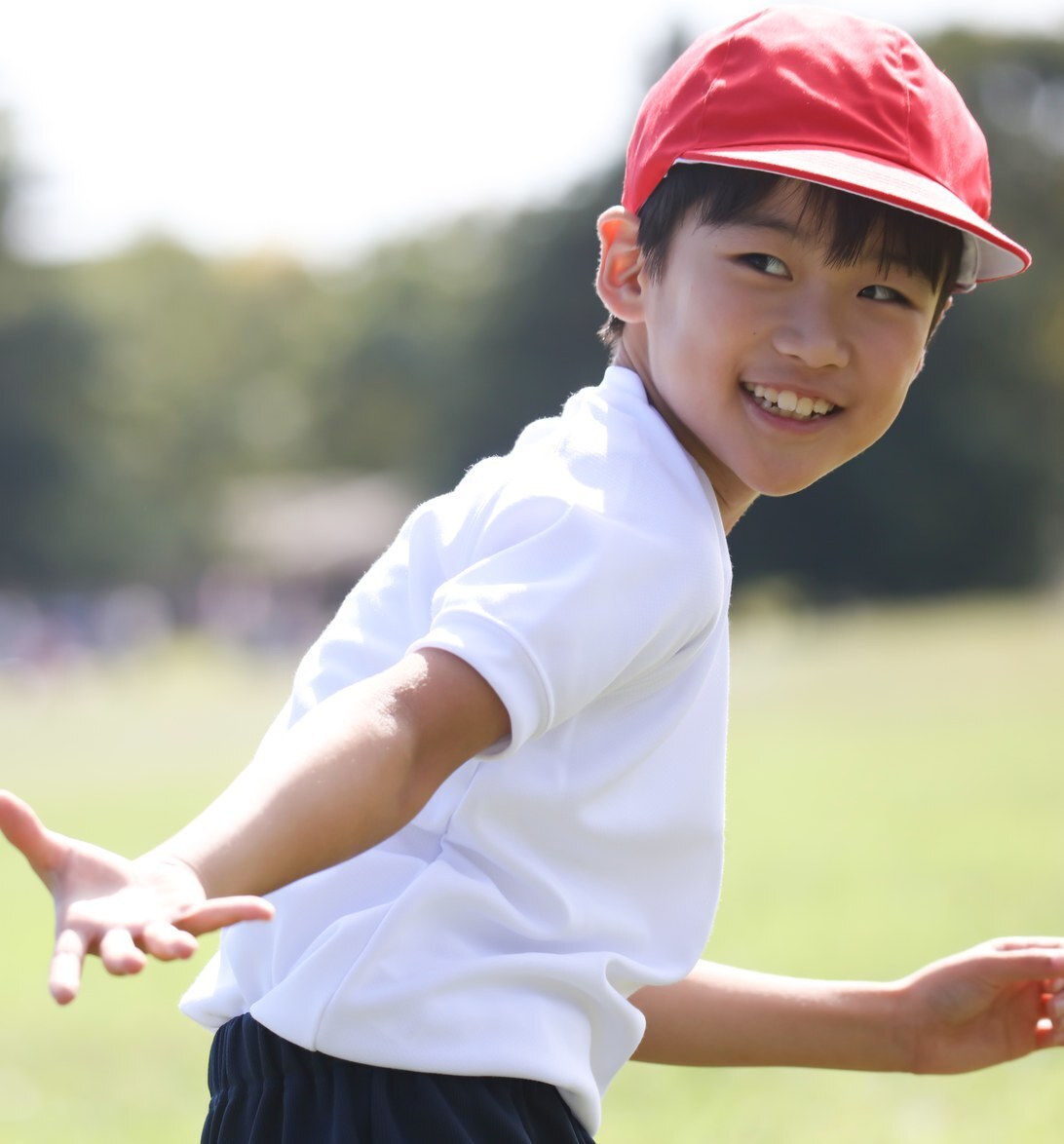 Niño con gorra roja sonriendo al aire libre