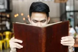 Hombre sosteniendo un libro muy cerca de su rostro