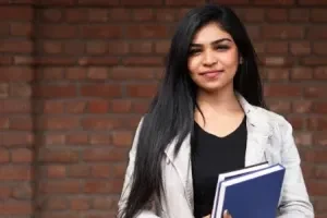 Joven de pie con cuadernos en la mano