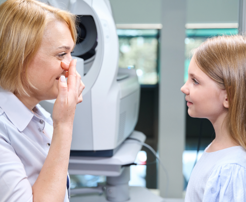 Profesional de la visión y niña junto a un equipo de examen ocular