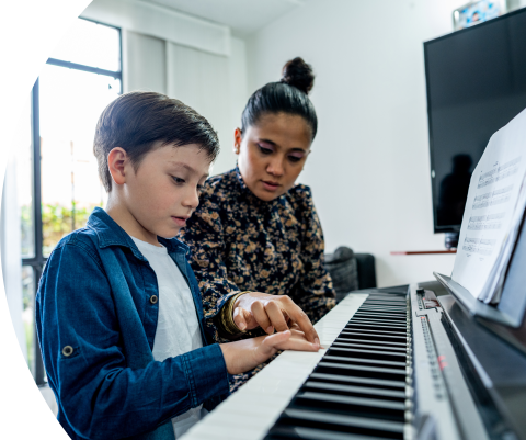 Niño tocando el piano acompañado por su madre